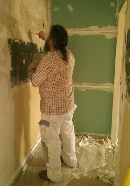 Ein Mann verspachtelt in einem kahlen Raum eine Wand