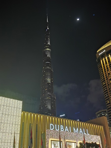 Der Burj Khalifa am dunklen Abendhimmel und im Vordergrund der Eingang zur Dubai Mall