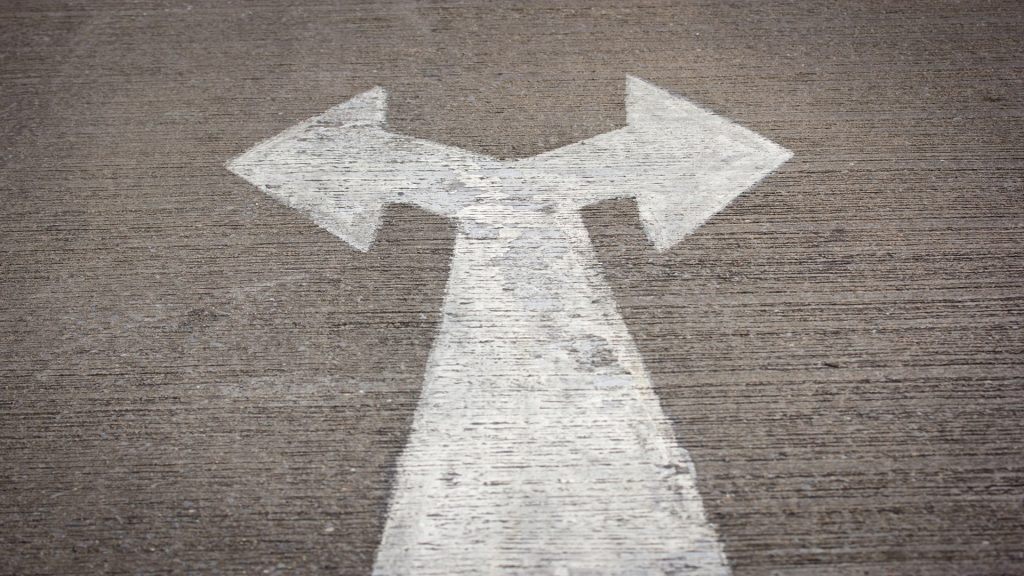 Auf Asphalt in weiß gemalter Pfeil, der sowohl nach rechts, als auch nach links, zeigt