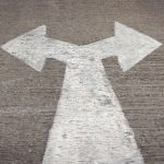 Auf Asphalt in weiß gemalter Pfeil, der sowohl nach rechts, als auch nach links, zeigt