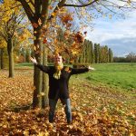 Alexandra steht mitten in einem Laubhaufen und schmeißt die Blätter in die Luft