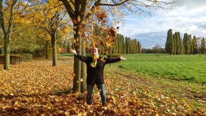 Alexandra steht mitten in einem Laubhaufen und schmeißt die Blätter in die Luft
