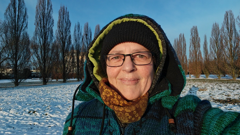 Beitragsbild zum Blogartikel "Monatsrückblick Januar2026". Alexandra steht, dick in Winterklamotten eingepackt auf einer mit Schnee bedeckten Wiese und lässt sich die Sonne ins Gesicht scheinen.